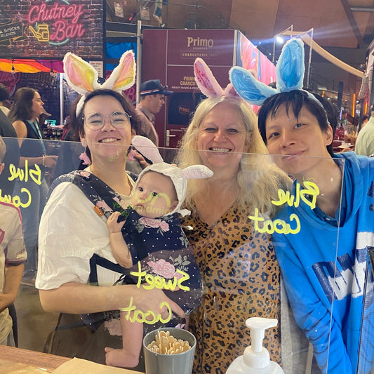 Three people and a baby wearing bunny ears with text on a counter in a casual setting